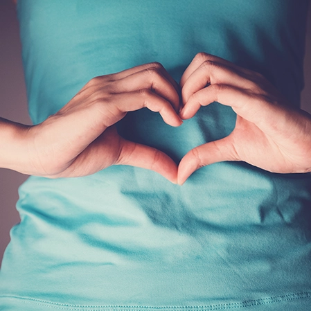 A person making heart shape over their stomach.