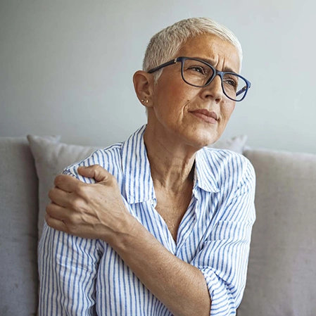 A woman holding her shoulder in pain.