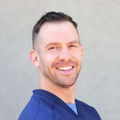 Ben Lanz smiling while wearing blue scrubs.
